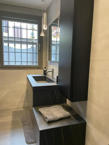 Mobile lavabo scuro e grandi lastre effetto resina in bagno contemporaneo